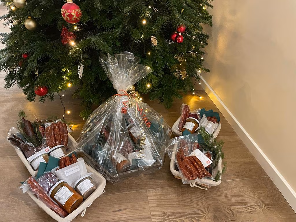 Mehrere verpackte Geschenkkörbe unter einem geschmückten Weihnachtsbaum