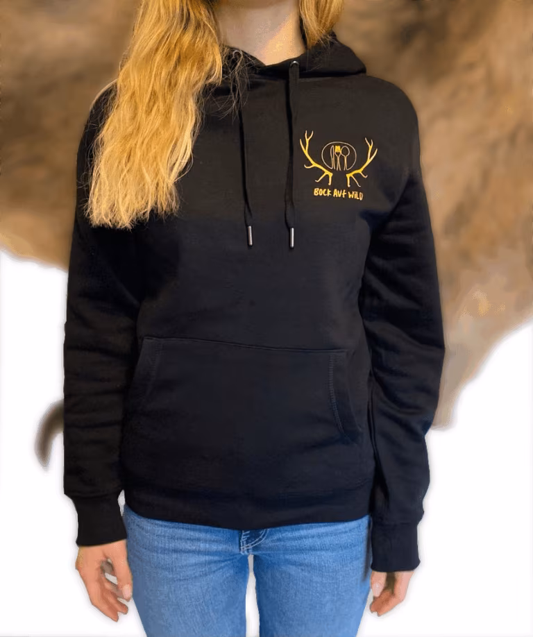 Frau in schwarzem Kapuzenpullover mit kleinem goldenem Geweih-Logo auf der Brust