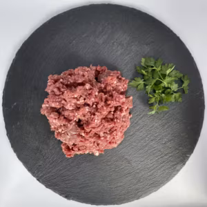 Rohes Hackfleisch mit Petersilie auf einer runden Schieferplatte
