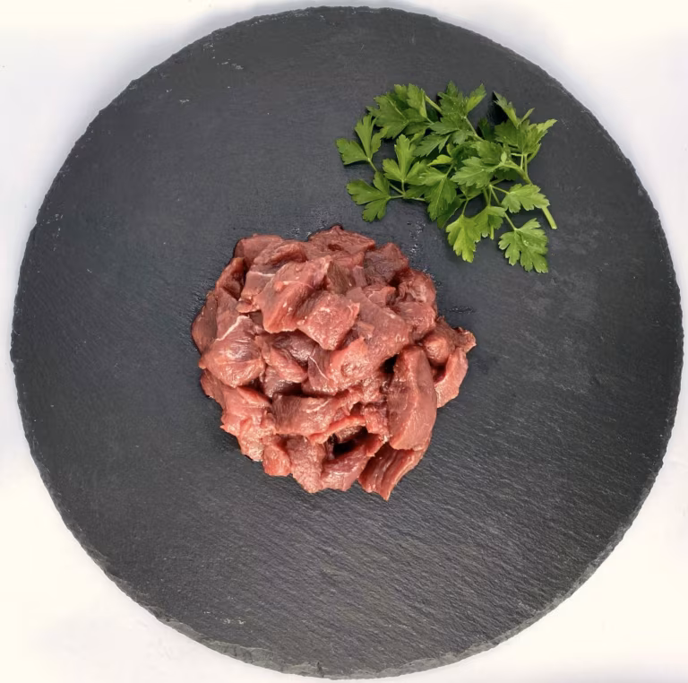 Rohes Gulaschfleisch mit Petersilie auf einer runden Schieferplatte