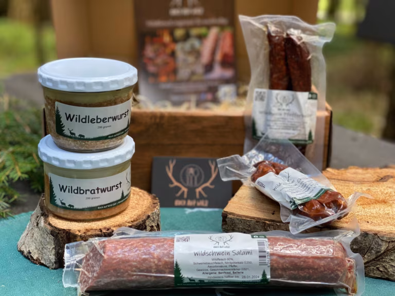 Kleine Brotzeitbox mit Wurstgläsern und geräucherten Würsten auf Baumscheiben