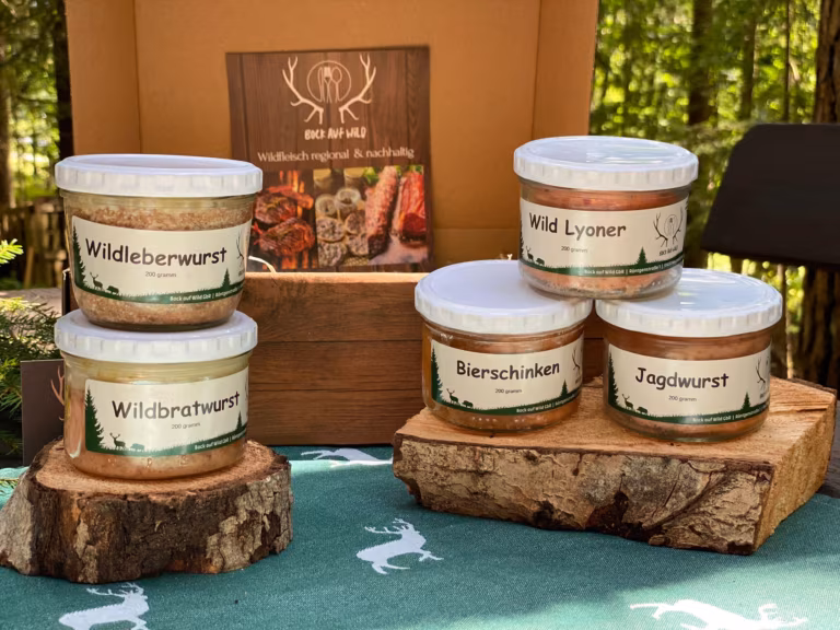 Fünf Gläser mit Wurstspezialitäten auf Baumscheiben vor einer Holzkiste
