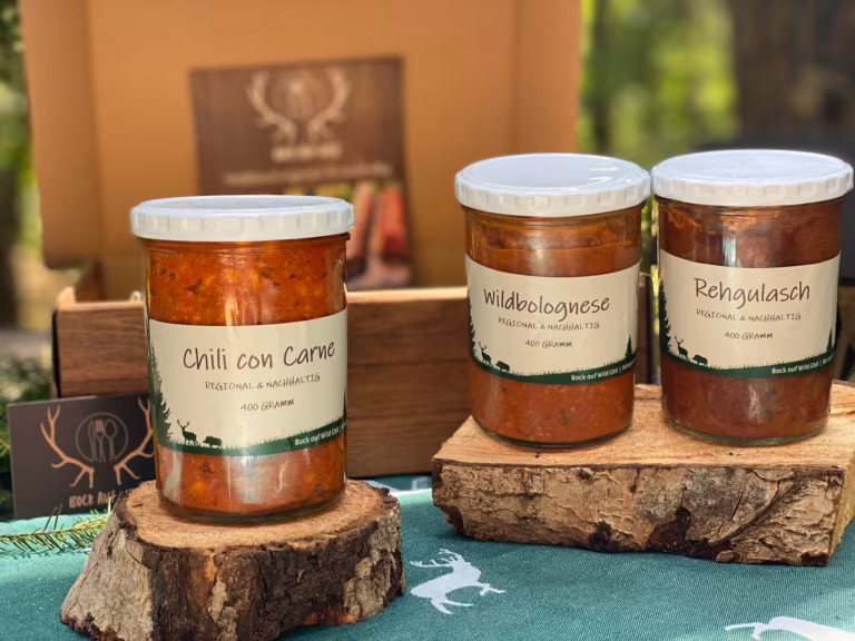 Drei Gläser mit Chili con Carne, Wildbolognese und Rehgulasch vor einer Holzkiste