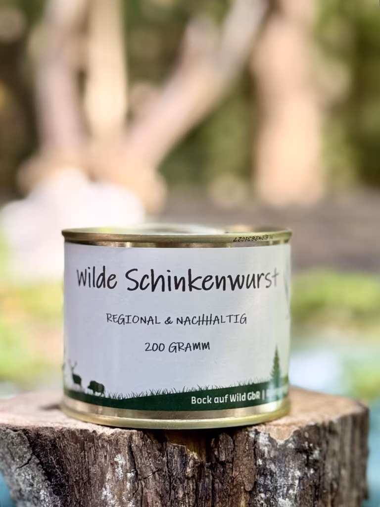 Konservendose Wilde Schinkenwurst auf einem Baumstumpf vor unscharfem Waldhintergrund