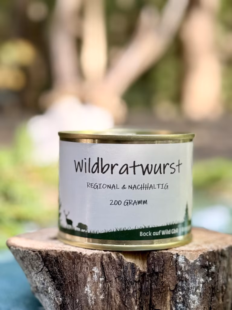 Konservendose Wildbratwurst auf einem Baumstumpf vor unscharfem Waldhintergrund