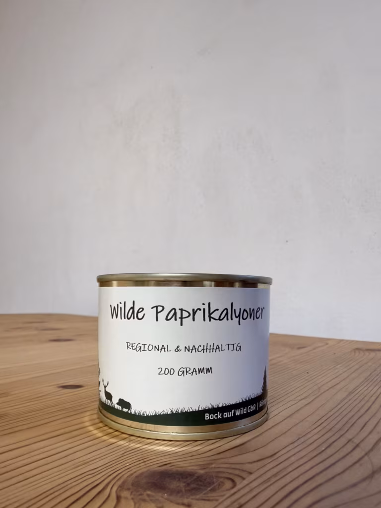 Konservendose Wilde Paprikalyoner auf einem Holztisch vor heller Wand